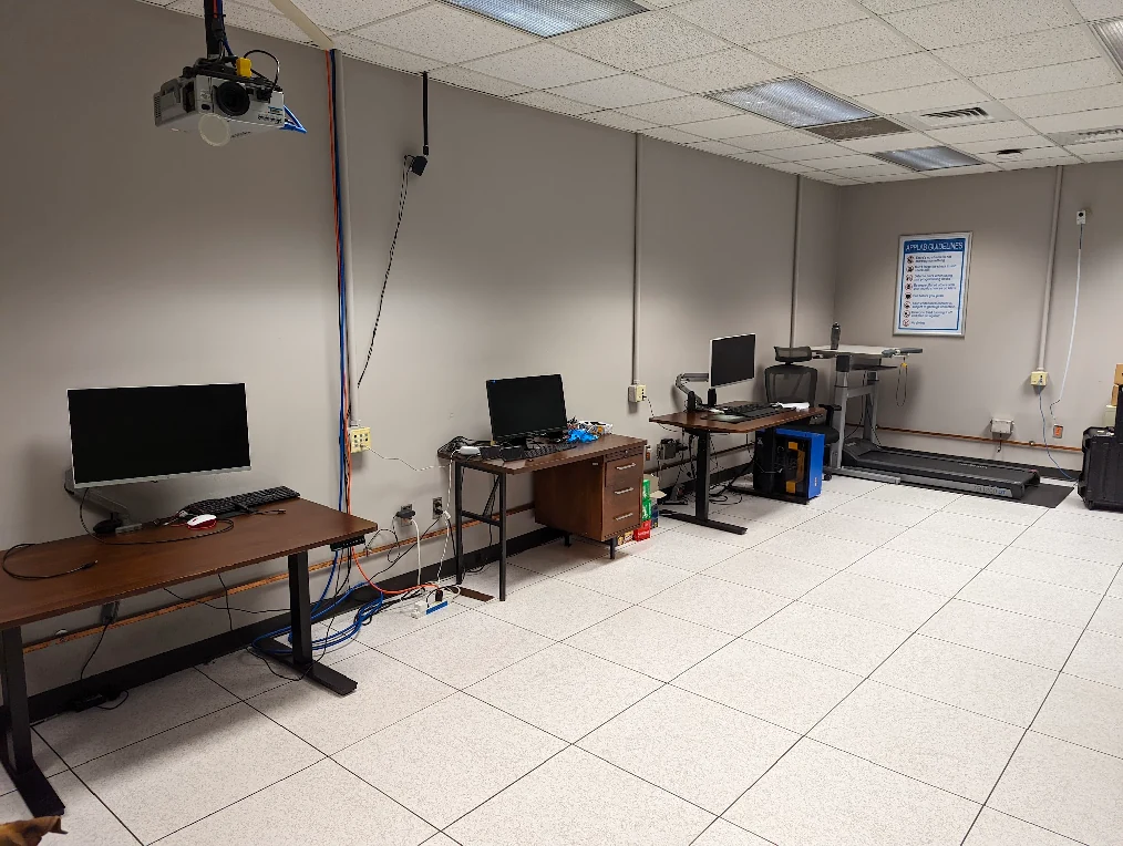 The early App Lab with mismatched desks, chairs and monitors on a raised tile floor.