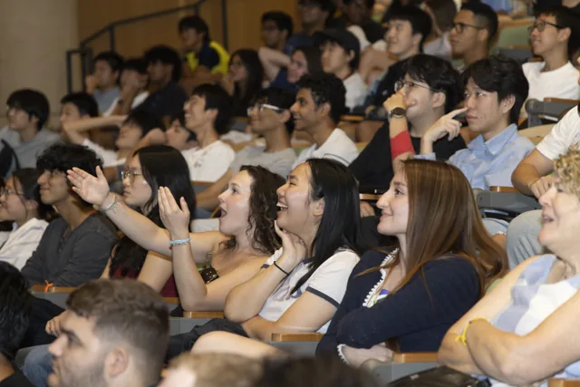 A closer view of students smiling, cheering and raising their hands while watching the race